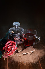 Obraz na płótnie Canvas hibiscus tea in a mug on a brown table with chocolate background