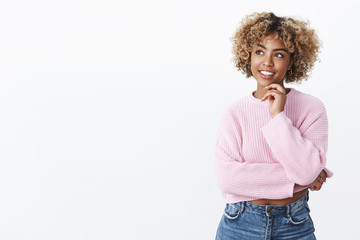 Attractive young african-american female student with blond hair holding hand on chin and looking...