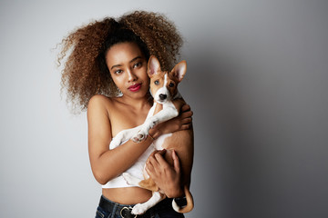 Handsome black african female with afro hair hugging her puppy basenji dog. Love between dog and owner. On white background.
