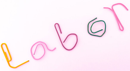 paper clip bend to the word labor to celebrate labor day in May. with light associate with the proud parade.