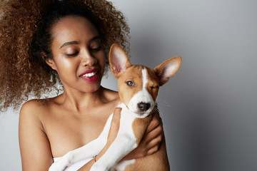Handsome black american african girl embracing puppy on white background. Studio portrait of white appealing female chilling with dog on white background