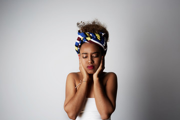 Young african girl with Afro curly hairstyle, posing aside with closed eyes, isolated over bright light backgroud. Advertisement and ethnicity.