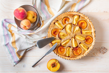 Fototapeta na wymiar Homemade open peach pie on a white wooden background.