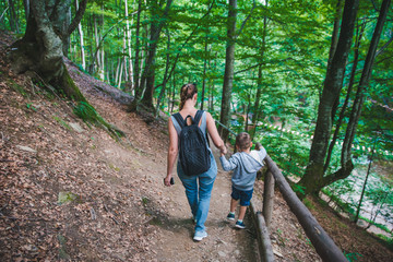 Naklejka na ściany i meble mother with son walking forest trail holding hands