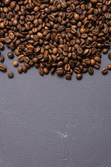 Roasted coffee beans in bulk on a gray concrete background. dark cofee roasted grain flavor aroma cafe, natural coffe shop background, top view from above, copy space