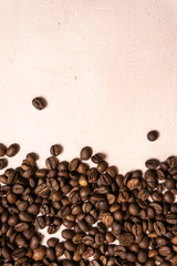 Roasted coffee beans in bulk on a light pink background. dark cofee roasted grain flavor aroma cafe, natural coffe shop background, top view from above, copy space