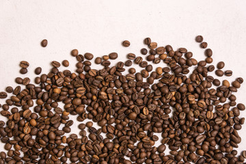 Roasted coffee beans in bulk on a light pink background. dark cofee roasted grain flavor aroma cafe, natural coffe shop background, top view from above, copy space