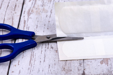 blue scissors cuts a plaster open