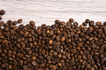 Roasted coffee beans in bulk on a light wooden background. dark cofee roasted grain flavor aroma cafe, natural coffe shop background, top view from above, copy space