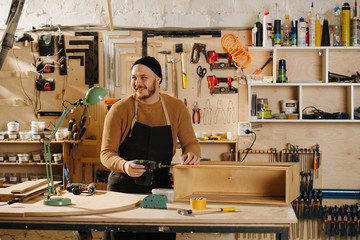 Carpenter is making furniture on order in a workshop.