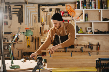 Carpenter is making furniture on order in a workshop.