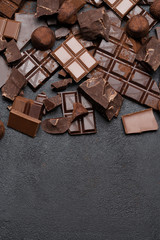 Dark or milk organic chocolate pieces, cocoa powder and truffle candies on dark concrete backgound