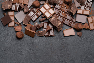 Dark or milk organic chocolate pieces, cocoa powder and truffle candies on dark concrete backgound