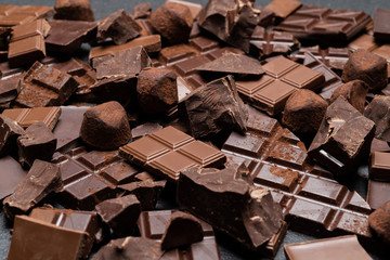 Dark or milk organic chocolate pieces, cocoa powder and truffle candies on dark concrete backgound