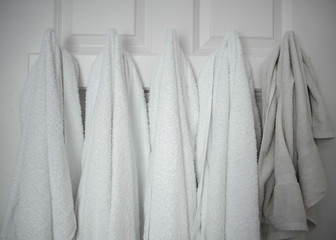five white and beige towels on hooks