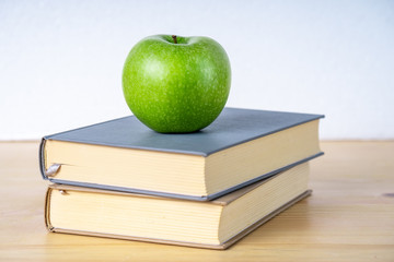 Two books and green apple on the wooden table