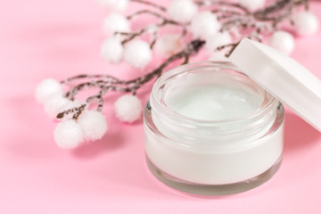 Cosmetic cream container on pink background with flowers. Face cream. Hand and face care. Day cream