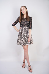 cute caucasian girl in a lace black dress stands on a white background in the Studio