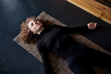 woman practicing in a yoga studio resting in shavasana or corps pose
