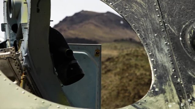 A steady, extreme close up, racking focus of the mountains seen through an oval hole.