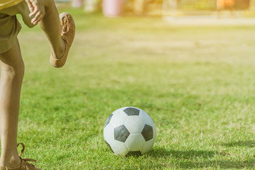 Obraz premium Asian boys practice kicking the ball to score goals in the public football field.