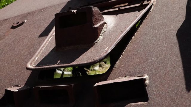 A hand held, extreme close up shot of a trap door covered in rust. 