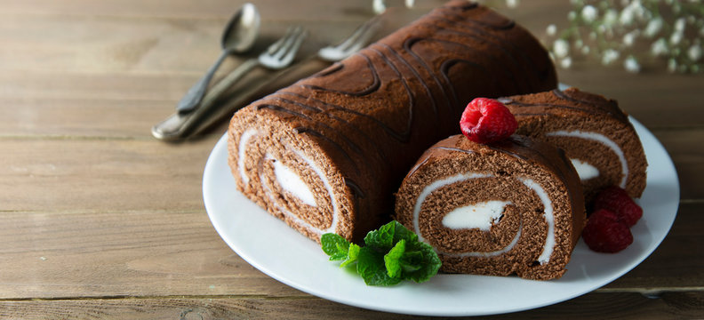 Delicious chocolate roll sponge cake with vanilla cream and mint leaves. Desert sweet food. Banner