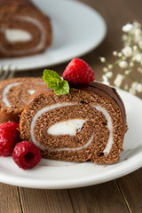 Delicious chocolate roll sponge cake with vanilla cream and mint leaves. Desert sweet food.