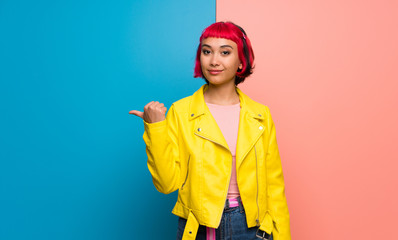 Young woman with yellow jacket pointing to the side to present a product