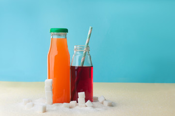 Glass bottles with orange and cherry juice near sugar