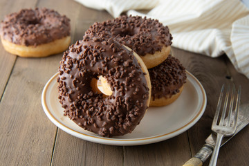 Chocolate donuts breakfast or dessert, wooden table. Close up glazed donuts. Sweet food. Pastry.