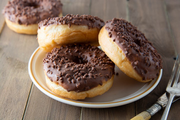 Chocolate donuts breakfast or dessert, wooden table. Close up glazed donuts. Sweet food. Pastry.