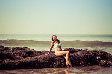 Portrait of a young woman on the background of waves and stones