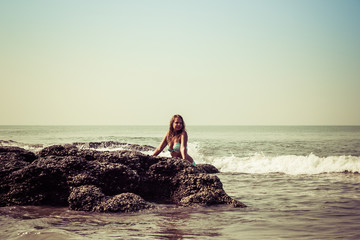 Portrait of a young woman on the background of waves and stones
