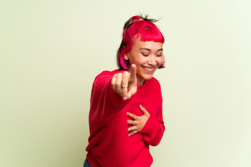 Young woman with red sweater pointing with finger at someone and laughing a lot