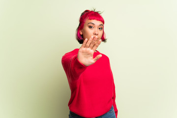 Young woman with red sweater making stop gesture denying a situation that thinks wrong