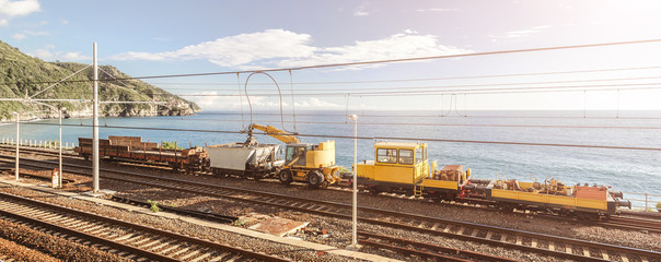 A train with heavy duty machinery on Italian railroad going along the coast near Cinque Terre , Liguria Italy Europe.