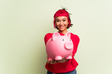 Fototapeta na wymiar Young woman with red sweater holding a piggybank