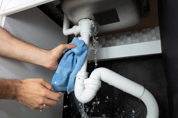 Male Hand's Holding Blue Napkin Under Leakage Pipe
