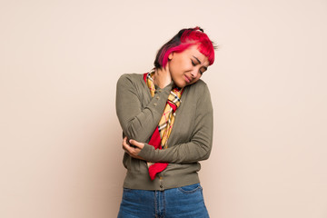 Young woman with pink hair over yellow wall with neckache