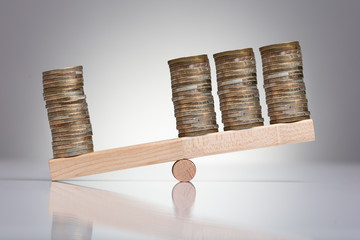 Stack Of Coins On Wooden Seesaw