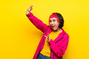 Young woman with pink hair over yellow wall nervous and scared