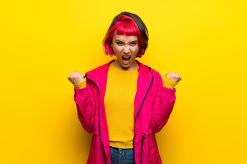 Young woman with pink hair over yellow wall frustrated by a bad situation