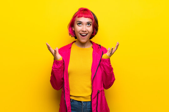Young woman with pink hair over yellow wall frustrated by a bad situation