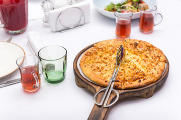 cheese pizza on a wooden tray on the table