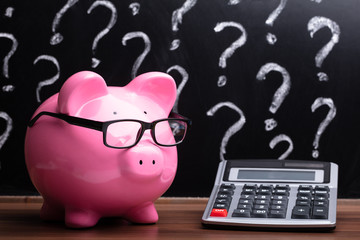 Piggybank With Eyeglasses And Calculator On Desk