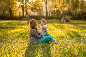 Fototapeta premium Mom and baby in a summer Park at sunset.