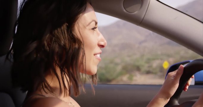 Young woman smiling and laughing as she drives sports car - close up on face