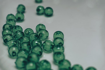 Green glass beads on a white background. Macro view.