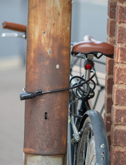 close up of rusty old bicycle locked to lampost in an urban street